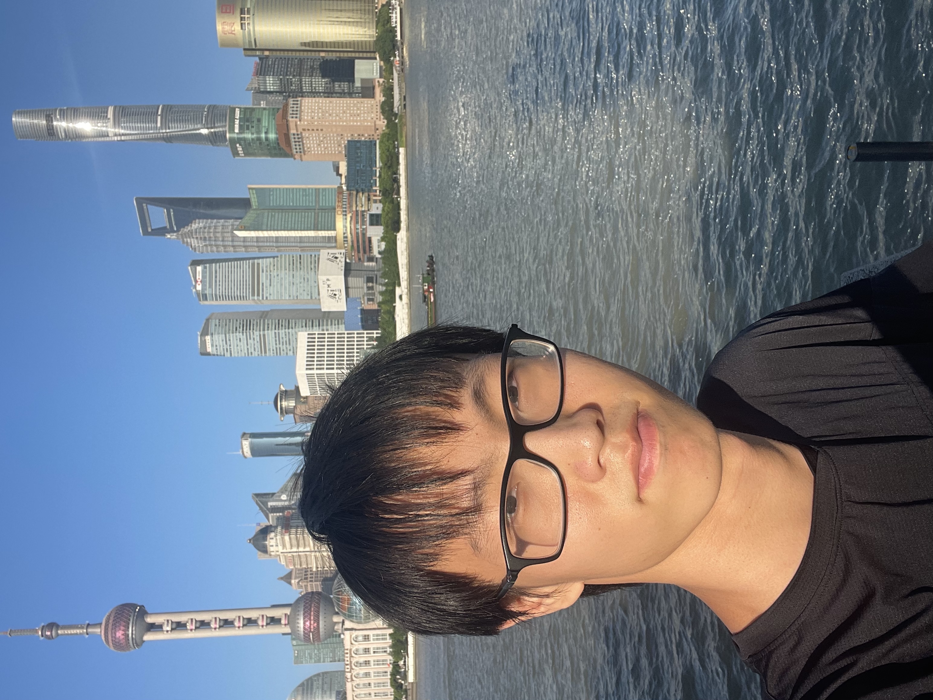 Bingchen beside the river with the Shanghai skyline behind him